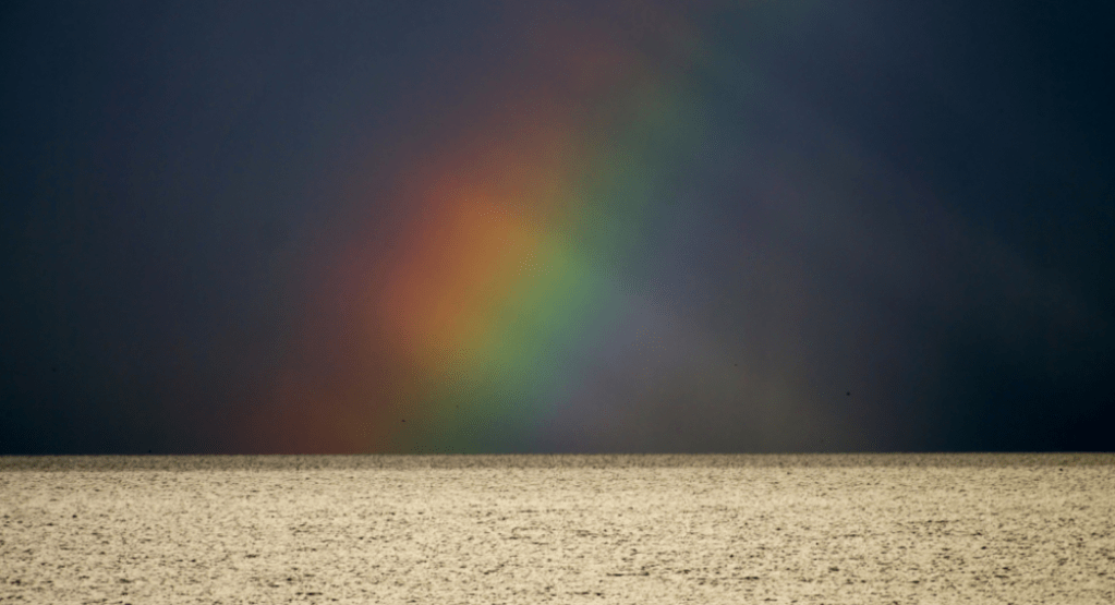 Een door wolken gefragmenteerde regenboog op het IJsselmeer - Foto © G. van Keulen